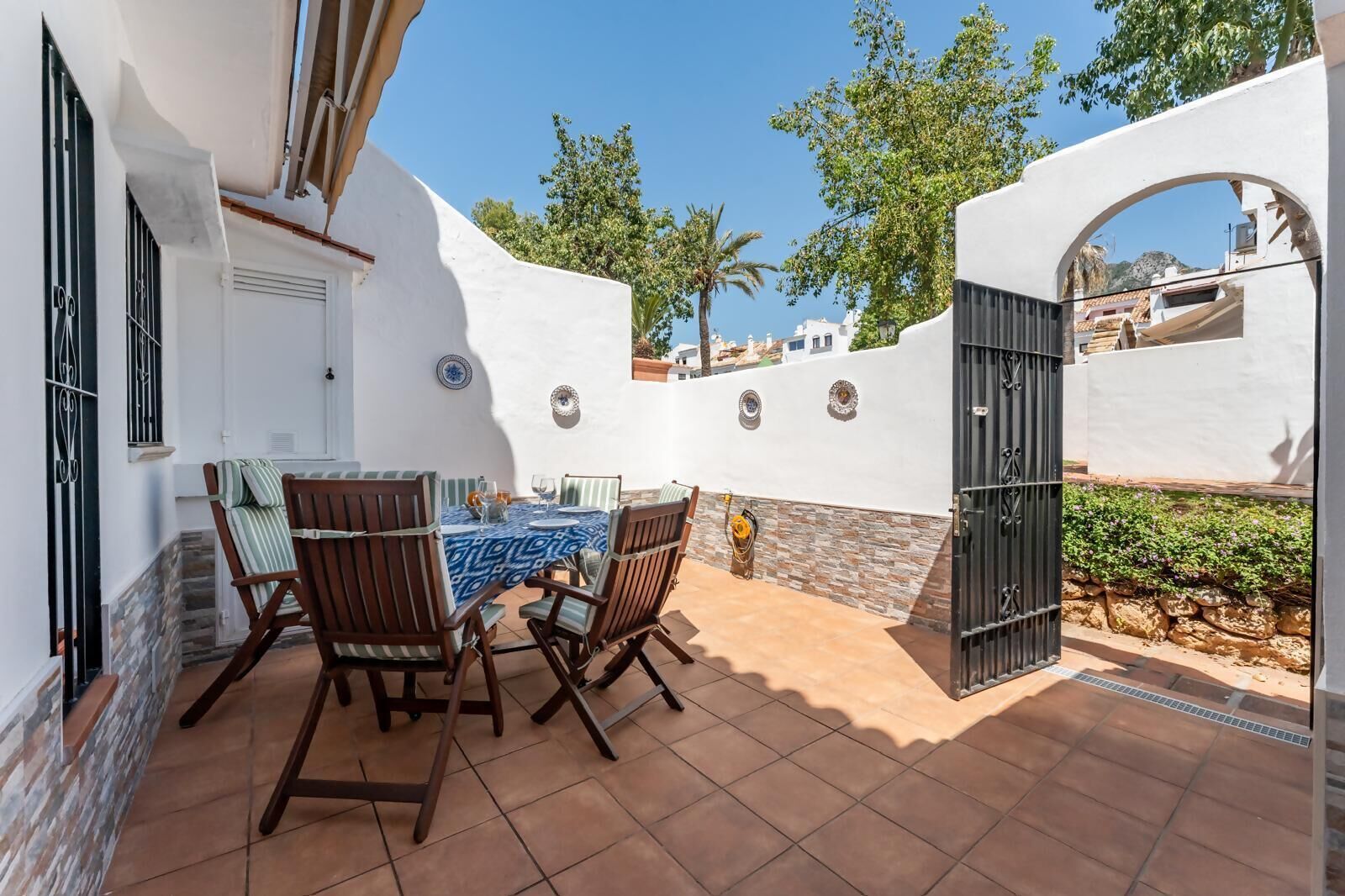 A patio with a table and chairs, a door, and a wall with decorative plates.