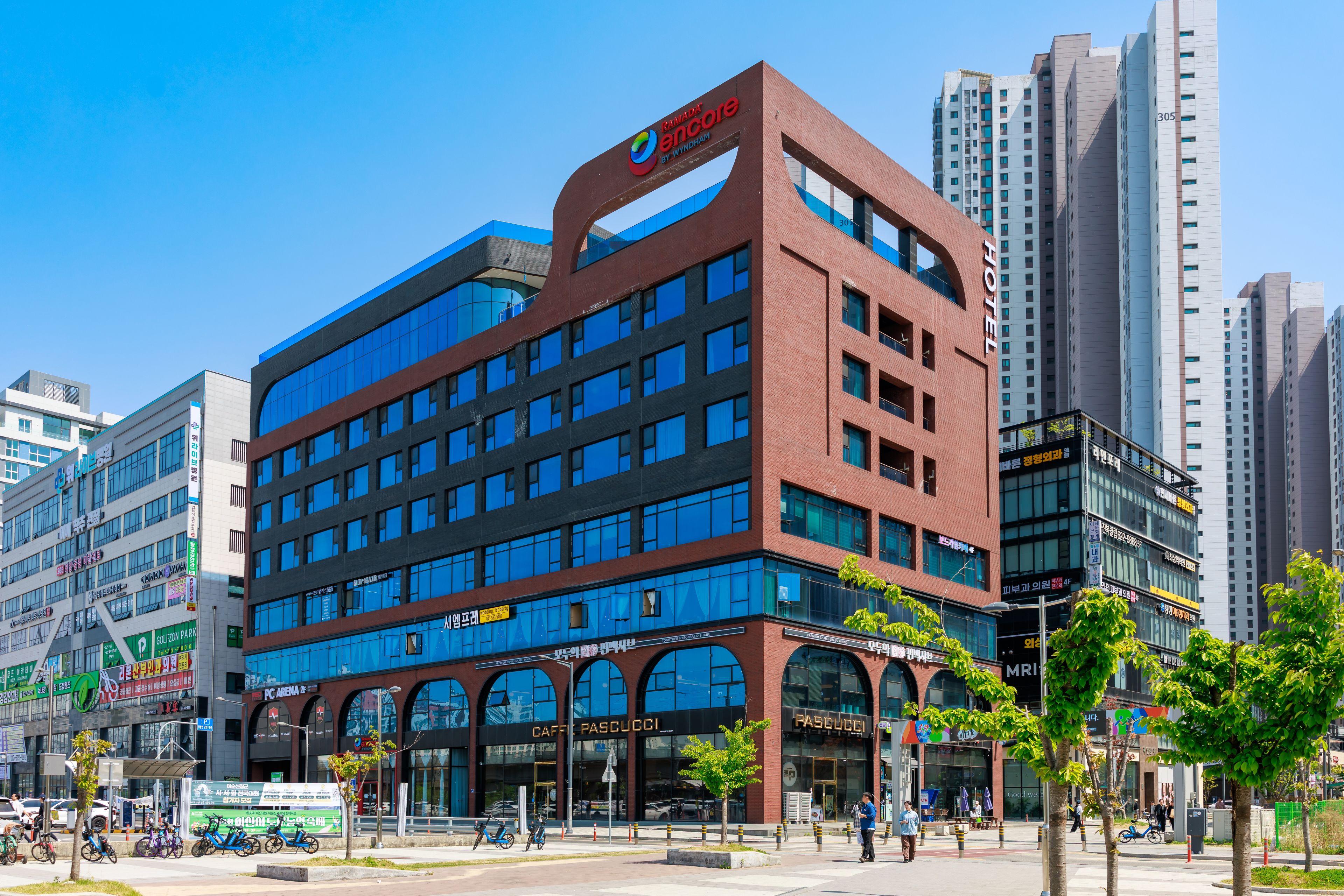 A modern hotel with multiple floors, large windows, and a prominent sign for a nearby coffee shop.