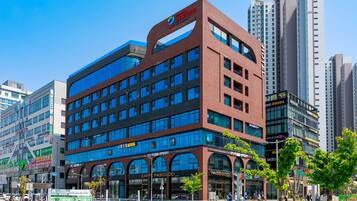A modern hotel with multiple floors, large windows, and a prominent sign for a nearby coffee shop.