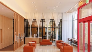 Um hall moderno com balcão de atendimento, área de estar e grandes janelas.