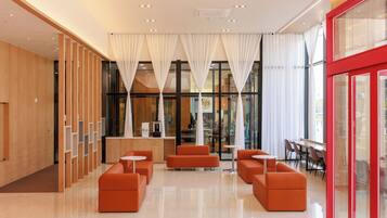 A modern lobby with a reception desk, seating area, and large windows.