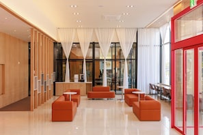 A modern lobby with a reception desk, seating area, and large windows. - Ramada Encore ASAN (Asan)
