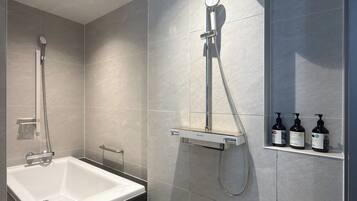 A modern bathroom with a bathtub, a shower with a handheld showerhead, and a shelf with toiletries.