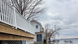 Une propriété située au bord de l’eau, dotée d’une terrasse en bois, d’un mur de soutènement en béton et d’un rivage rocheux.