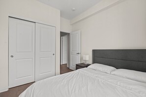 Ein Schlafzimmer mit einem Bett, einem Nachttisch, einer Lampe und einem Kleiderschrank.