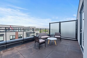 Ein Balkon mit Gartenmöbeln, einer Glastür und Blick auf Gebäude.