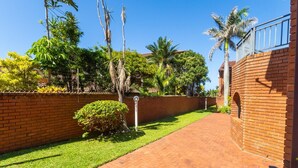A brick pathway leading to a building with a brick wall and a metal railing. - Central Location |Beach Access  | Patio (Margate)