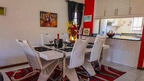 A dining area with a table set for four, chairs, a vase with flowers, and a painting on the wall. - Central Location |Beach Access  | Patio (Margate)