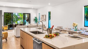 A modern kitchen with a large island, dining area, and a view of greenery outside. - Townhouse / Heated Pool / Centrally Located / Malibu Key Two (Fort Lauderdale)