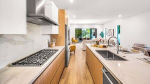 A modern kitchen with a central island, stainless steel appliances, and a view into the living area. - Townhouse / Heated Pool / Centrally Located / Malibu Key Two (Fort Lauderdale)