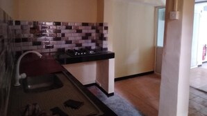 A small kitchen with a tiled backsplash, a gas stove, and a sink.