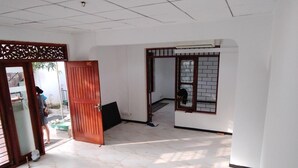 A room with a tiled floor, a wooden door, and a window with a metal grille.