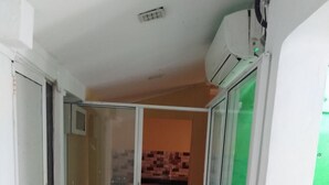 A corridor with a tiled floor, a sliding glass door leading to a kitchen, and an air conditioning unit mounted on the wall.