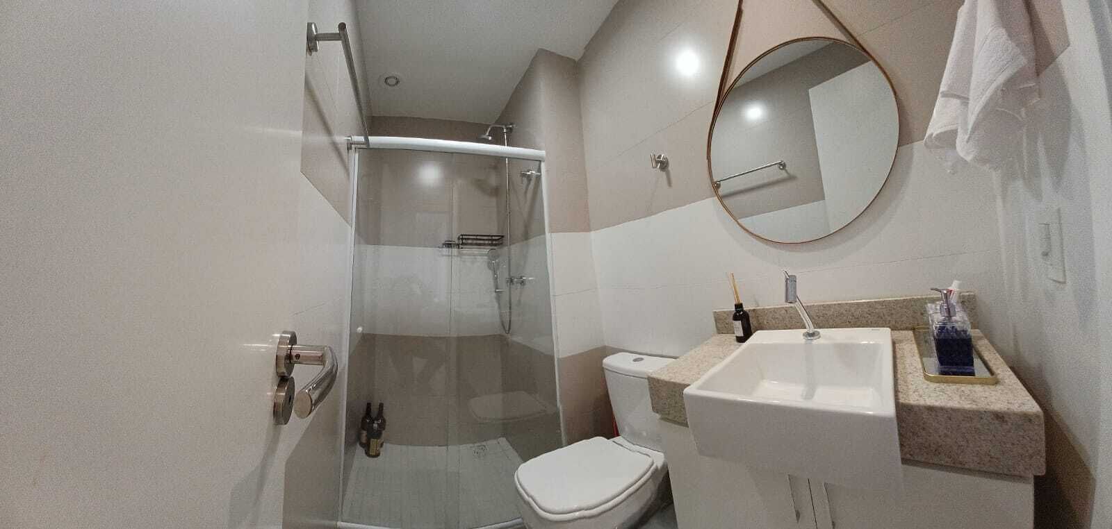 A modern bathroom with a glass-enclosed shower, a toilet, a sink with a countertop, and a mirror.
