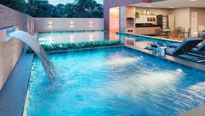 A swimming pool with a waterfall feature, a bar area, and a seating area with lounge chairs. - Fantastic Apartment by the Beach, 24/7 Security, Parking Garage (Vila Velha)