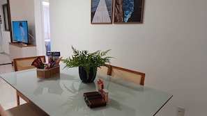 A dining area with a glass table, chairs, a potted plant, a small toy, and a snack basket.