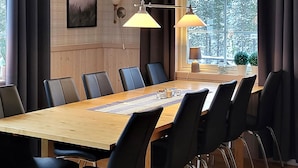 A conference room with a wooden table, black chairs, a striped placemat, and two wall-mounted lamps.