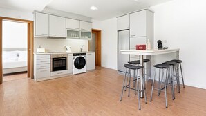 Ett modernt kök med inbyggd ugn, tvättmaskin och en matplats med barstolar.