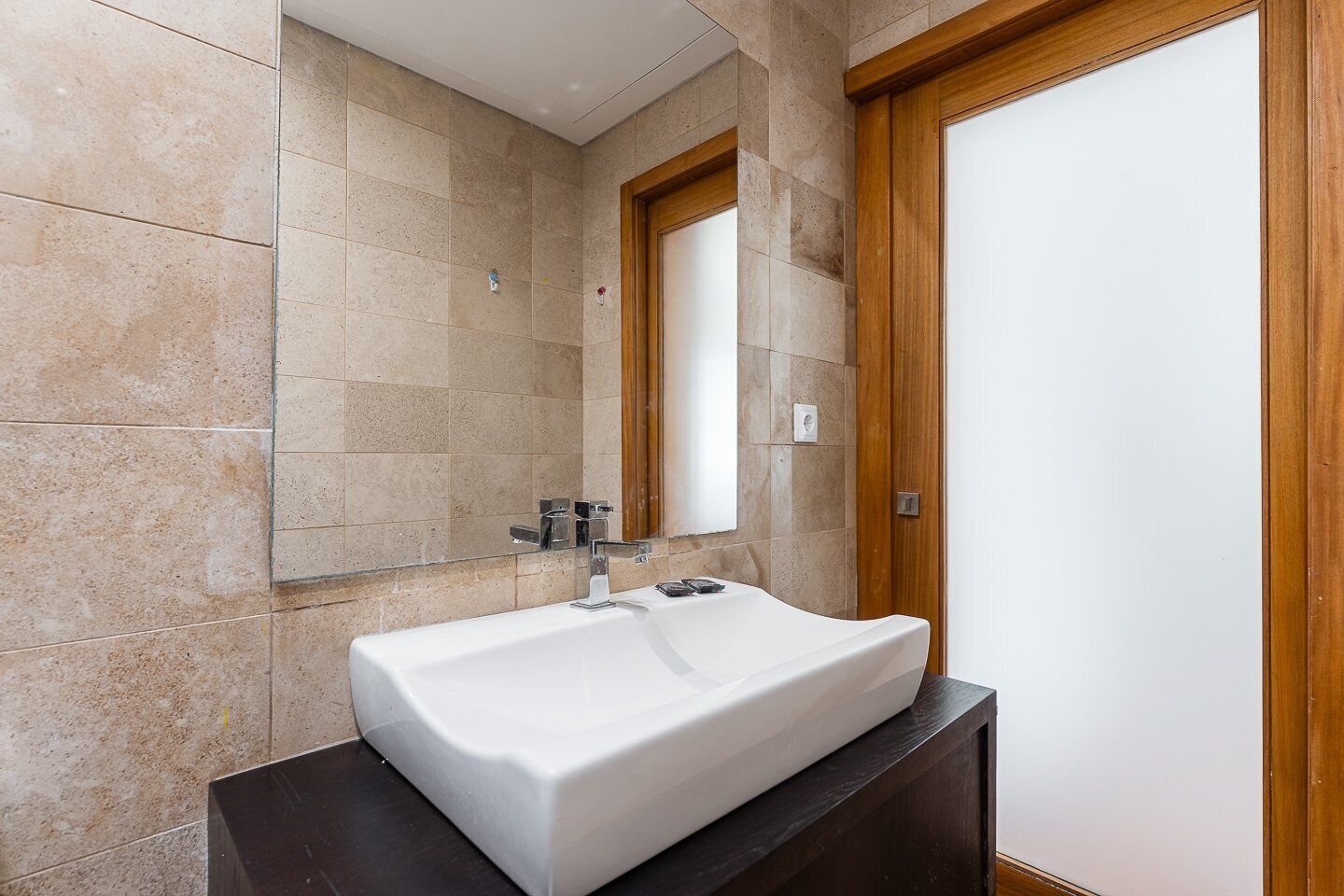 A bathroom with a white sink, a mirror, and a wooden door.