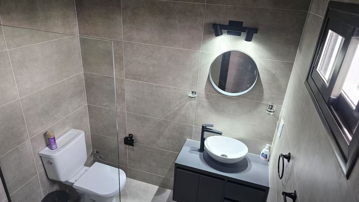 Une salle de bain moderne avec des toilettes, un lavabo et un miroir.