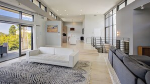 A spacious living area with a white sofa, a grey sofa, and a large rug. - Hollywood Hills - Universal Studios- 4Bedroom- Sunset Views!!! (Los Angeles)