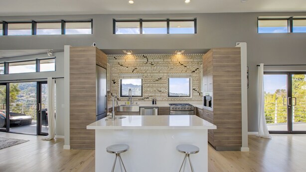 A modern kitchen with a central island, large windows, and a view of the outdoors. - Hollywood Hills - Universal Studios- 4Bedroom- Sunset Views!!! (Los Angeles)