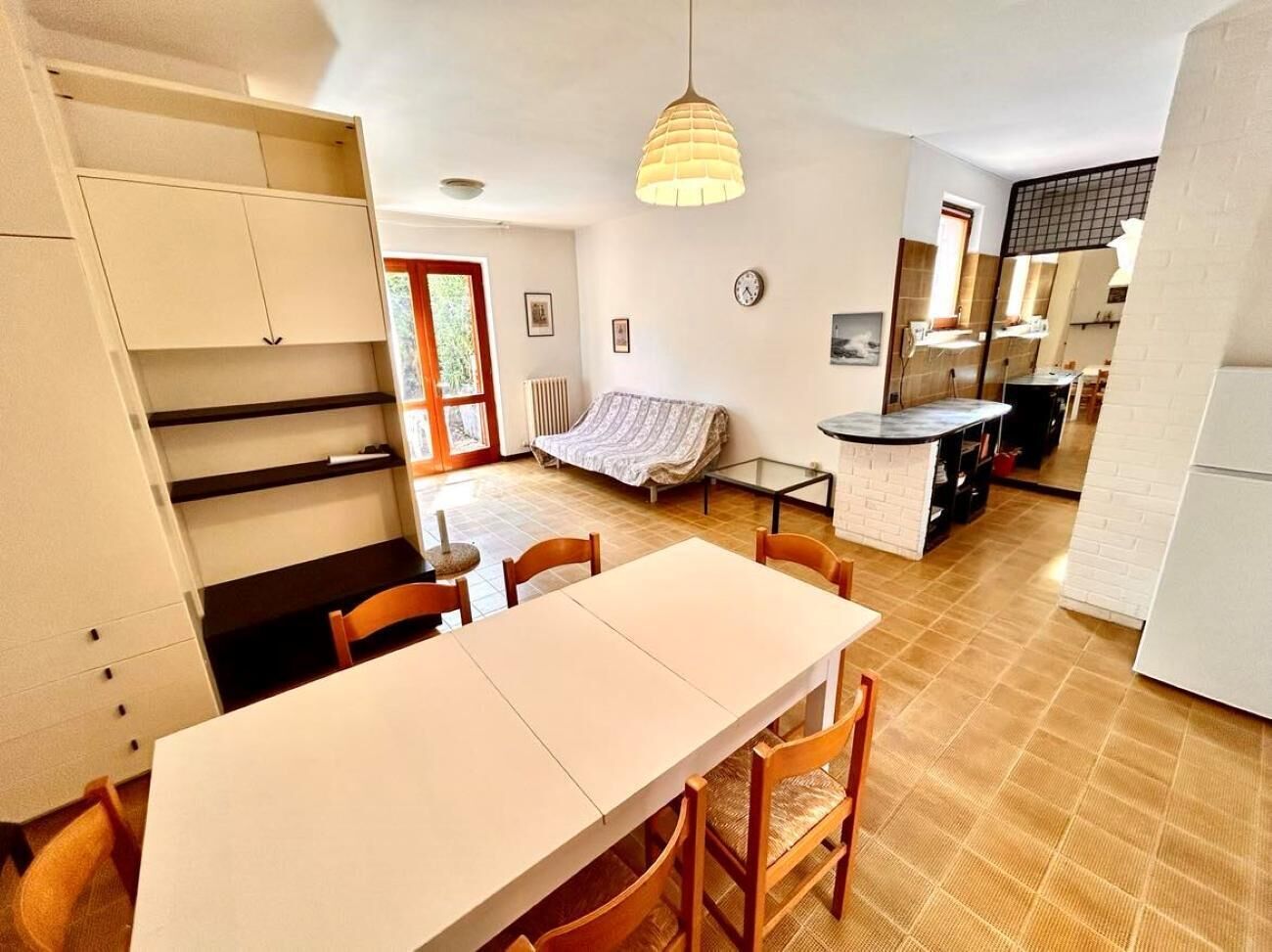 A compact kitchen with a dining area, a sofa, and a small table.