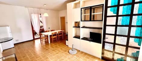 Un espacio habitable compacto con zona de comedor, kitchenette y un amplio ventanal con vistas.