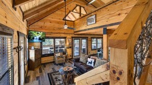 A log cabin interior with a wooden ceiling, a sofa, a coffee table, and a television. - Makin' Memories Cabin | Hot Tub, Views, Loft, Fire Pit & Game Area + FREE  Tickets (Sevierville)