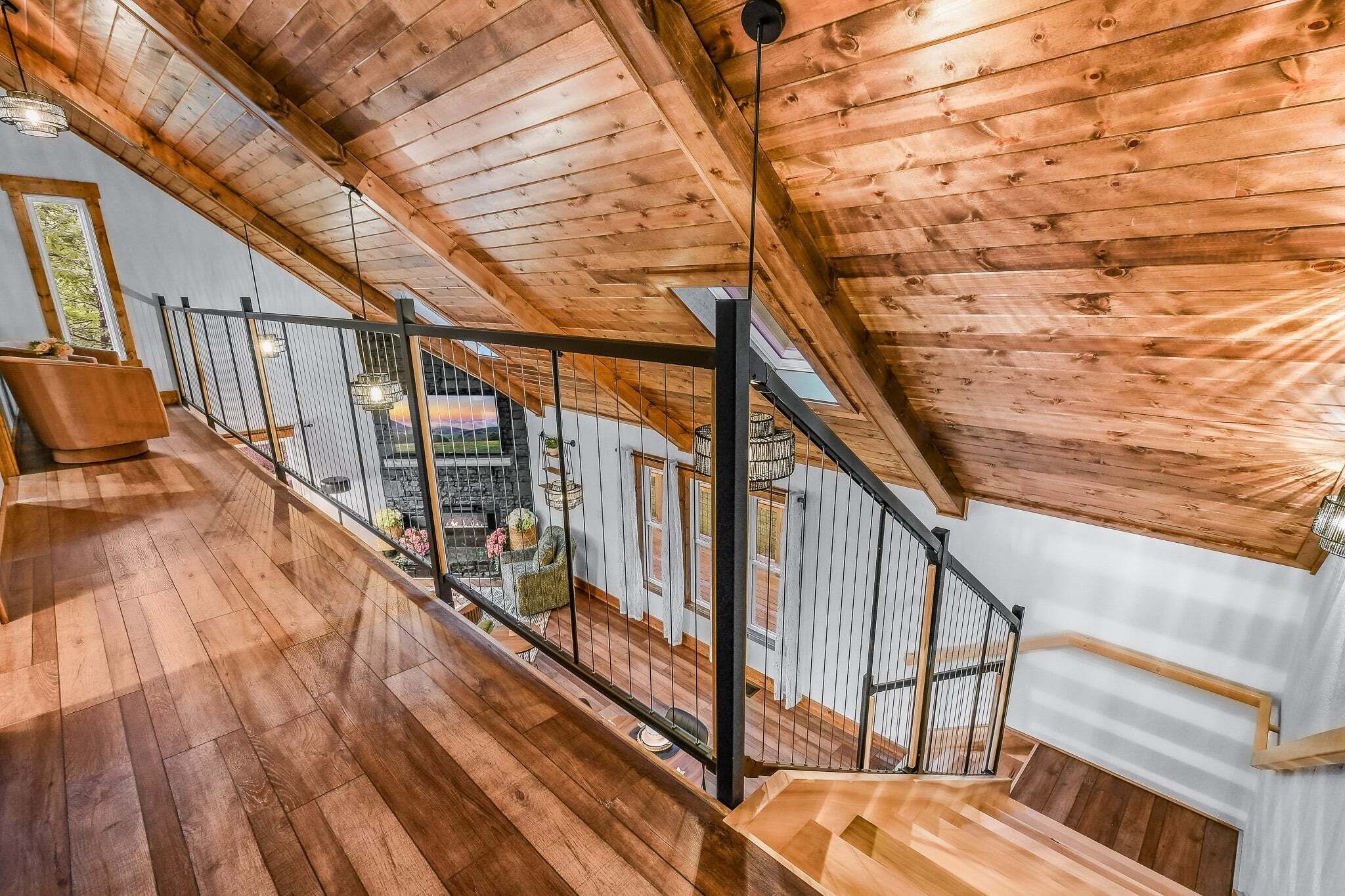 Una escalera de madera con barandilla de metal que lleva a un balcón con vistas al interior.