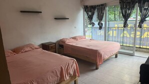 A room with two beds, a small table, a window with curtains, and a view of the outside. - HOTEL Y PIZZERIA CASA INN (Xalapa)