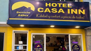 A two-story building with a yellow and blue facade, a sign for 'Hotel Casa Inn,' and a 24-hour service claim. - HOTEL Y PIZZERIA CASA INN (Xalapa)