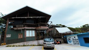 Un edificio con un balcón, un coche estacionado y un cartel del 'iSkuba Diving Center'.