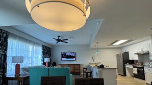 Een moderne woonkamer met een eettafel, een bank, een televisie en een keukenhoek.