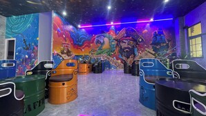 A room with a mural, ceiling fan, and seating area with barrels. - Win House Hotel (Phu Quoc)