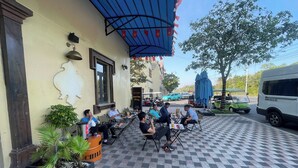 An outdoor seating area with tables and chairs, a blue awning, and a checkered floor. - Win House Hotel (Phu Quoc)