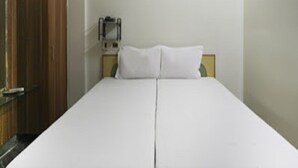A simple room with a bed, a wooden wardrobe, and a wall-mounted light fixture. - La Palace (Guduvancheri)