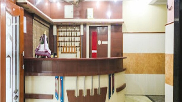 A reception area with a curved counter, a ceiling fan, and a patterned floor. - La Palace (Guduvancheri)