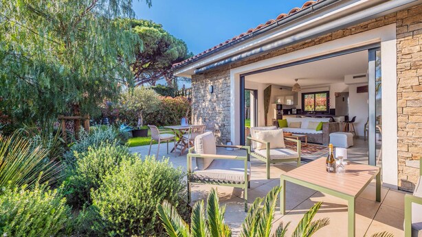 A modern house with a patio, outdoor furniture, and a stone wall. - SAINTE MAXIME Apartment with garden in residence with pool (STE MAXIME)