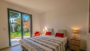 A bedroom with a bed, two bedside tables, a chair, and a sliding glass door leading to a garden. - SAINTE MAXIME Apartment with garden in residence with pool (STE MAXIME)