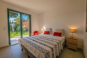 A bedroom with a bed, two bedside tables, a chair, and a sliding glass door leading to a garden. - SAINTE MAXIME Apartment with garden in residence with pool (STE MAXIME)