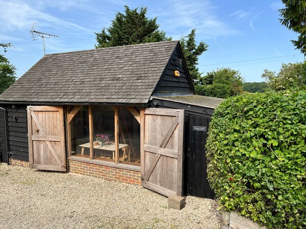 Un petit bâtiment en bois, doté d’un toit en pente, d’une porte d’entrée en verre et d’une enseigne indiquant « Mays Loft ».