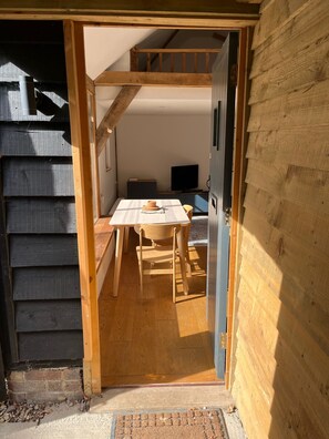 Un intérieur en bois avec une table et des chaises, un téléviseur et une porte donnant sur une autre pièce.