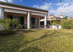 A house with a covered porch, outdoor seating, and potted plants. - Modern villa with air conditioning and garden, near Marina di Campo. (Marina di Campo)