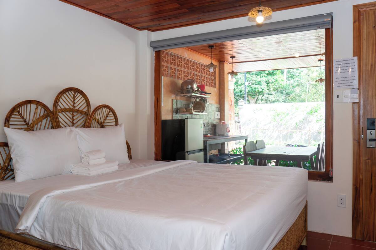 Un dormitorio con una cama grande, techo de madera, ventana con vistas y una pequeña mesa con sillas.