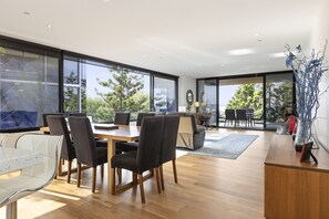 Un interior moderno con zona de comedor, sofá y vistas al exterior.