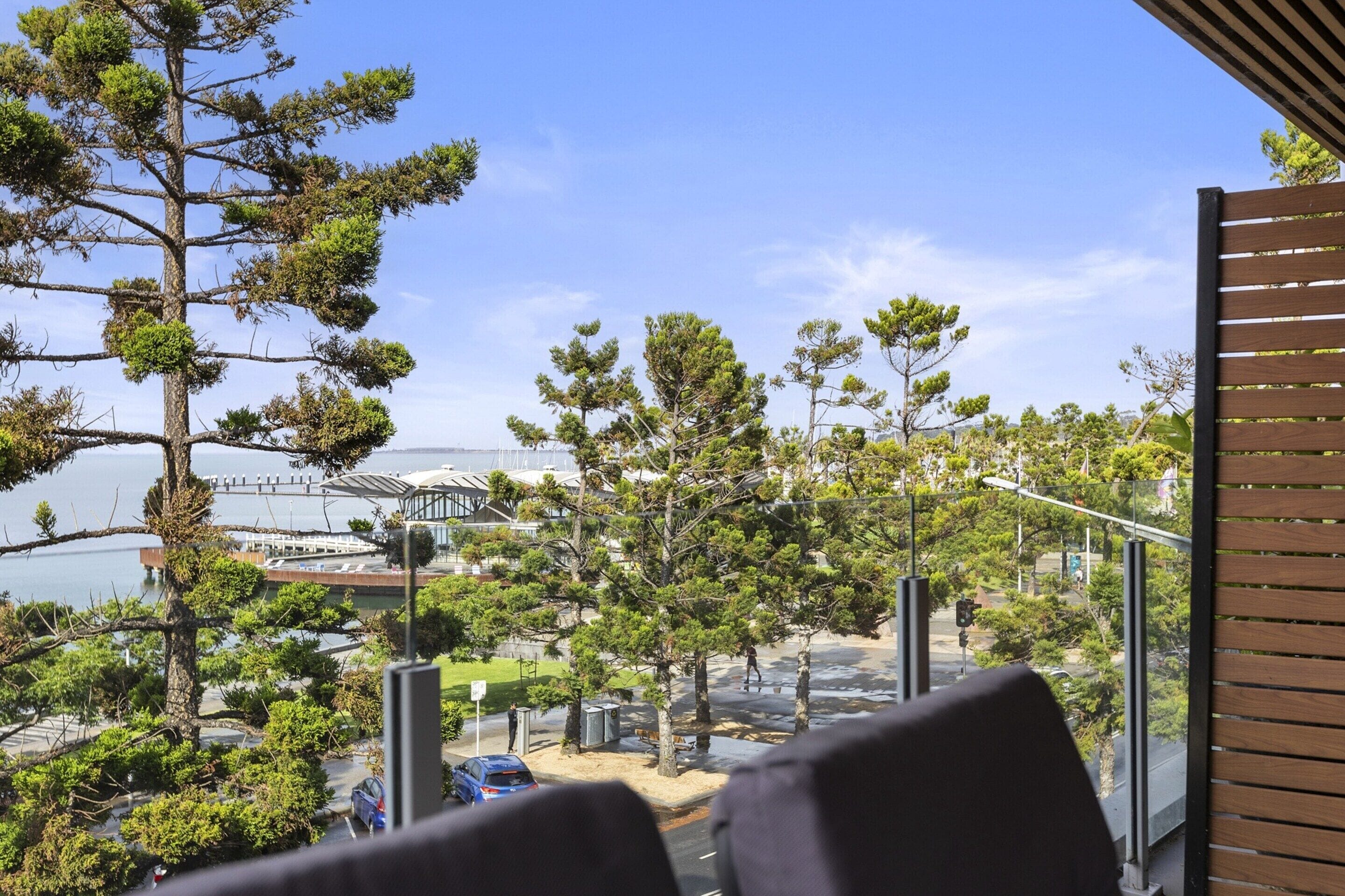 Un balcó amb vista a una zona costanera, incloent arbres i un pont a la distància.