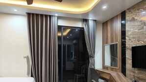 Ein Hotelzimmer mit einem Bett, einem Schreibtisch, einem Sessel, einem Telefon und einem Fernseher.