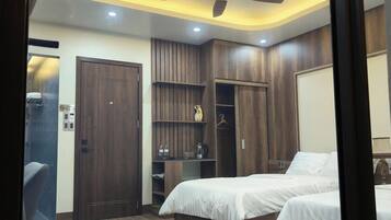 A bedroom with two beds, a ceiling fan, built-in wardrobe, and a small seating area.