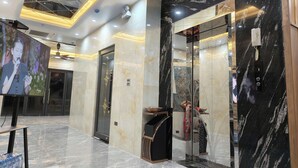 Eine Lobby mit Marmorboden, einem Empfangsbereich, einem Fernsehbildschirm und einer Glaselevator.